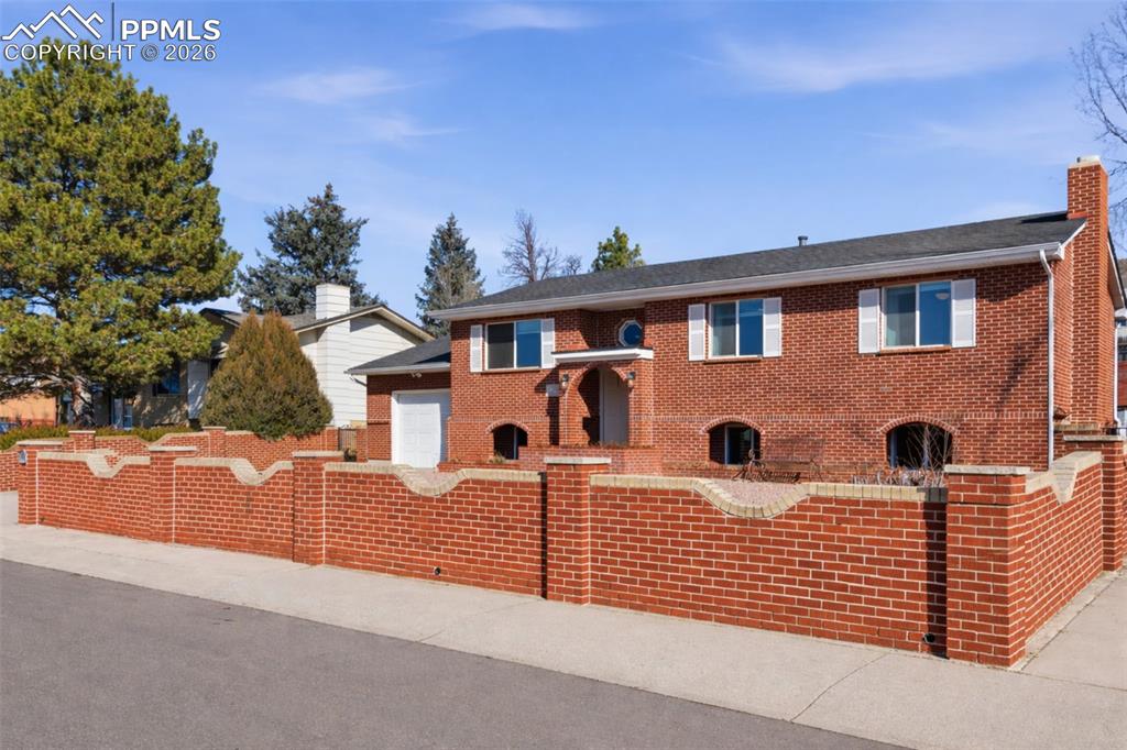 Image 1 of 50: View of front of house with a fenced front yard, brick siding, and a chimne