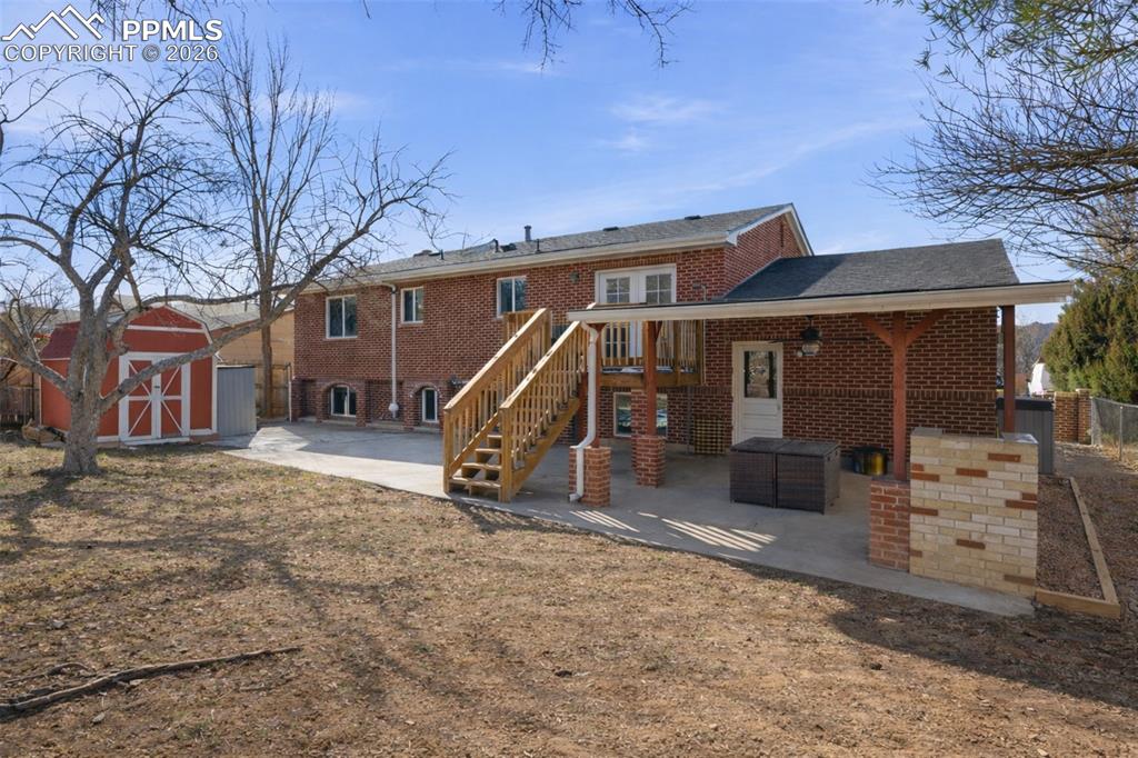 Image 36 of 50: Back of house featuring a storage shed, a patio, and brick siding