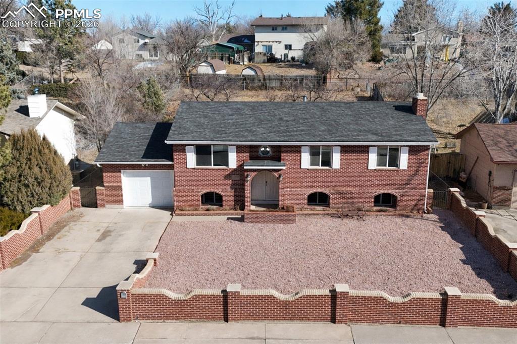 Image 39 of 50: View of front of house with concrete driveway, brick siding, a chimney, a s