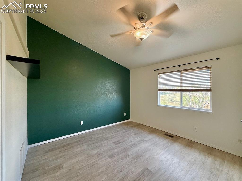 Image 12 of 37: Primary with light wood finished floors, lofted ceiling, and a ceiling fan