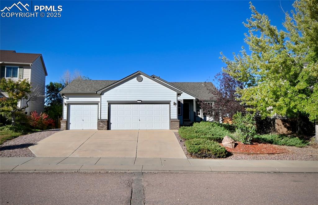 Image 2 of 37: Ranch-style house featuring brick siding, an attached garage, and driveway