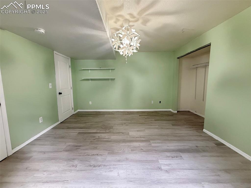 Image 30 of 37: Unfurnished bedroom, light wood-type flooring, and a chandelier