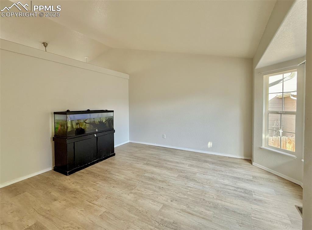 Image 6 of 37: Unfurnished living room with lofted ceiling and light wood finished floors