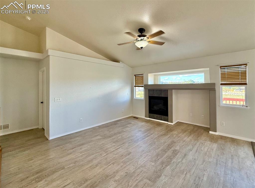 Image 7 of 37: Unfurnished living room with a tiled fireplace, light wood-type flooring, a