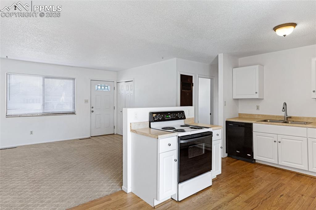Image 10 of 19: Kitchen with range with electric stovetop, light countertops, white cabinet
