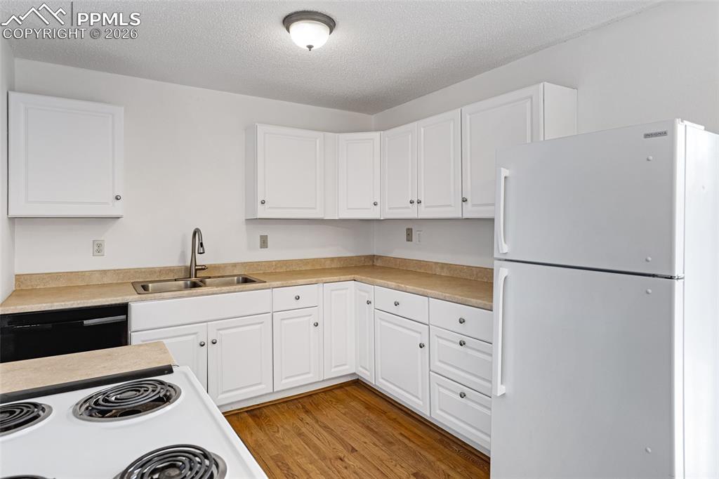 Image 11 of 19: Kitchen featuring white appliances, white cabinets, light countertops, ligh