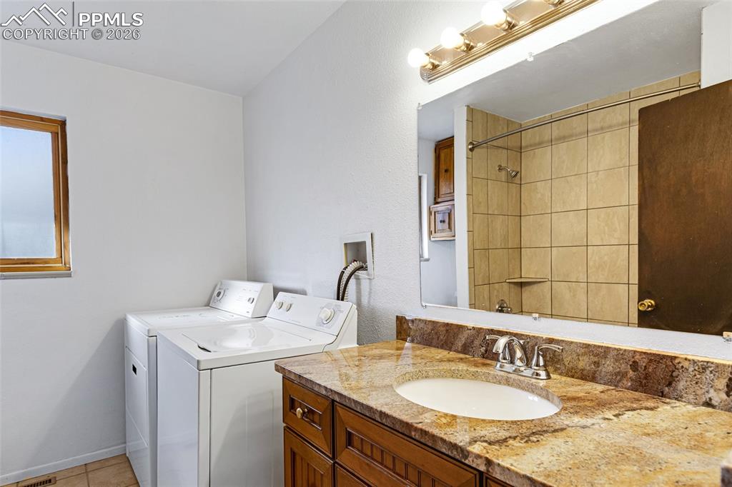 Image 15 of 19: Bathroom with two vanities, a shower, and independent washer and dryer