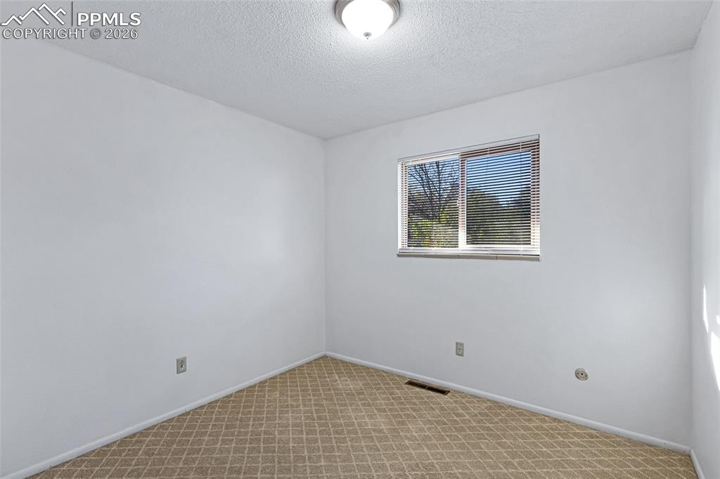 Image 17 of 19: Empty room with light colored carpet and a textured ceiling