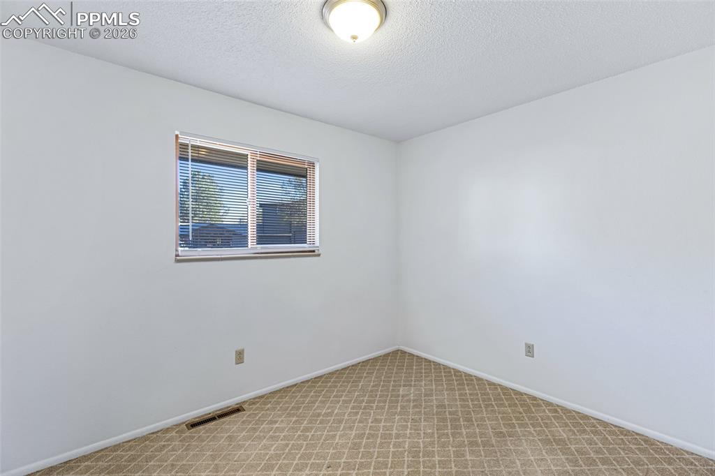 Image 18 of 19: Unfurnished room with light colored carpet and a textured ceiling
