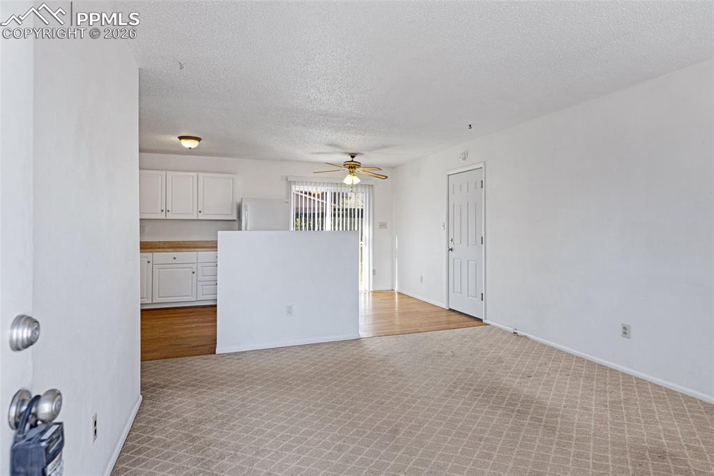 Image 7 of 19: Unfurnished living room featuring light carpet, ceiling fan, and a textured