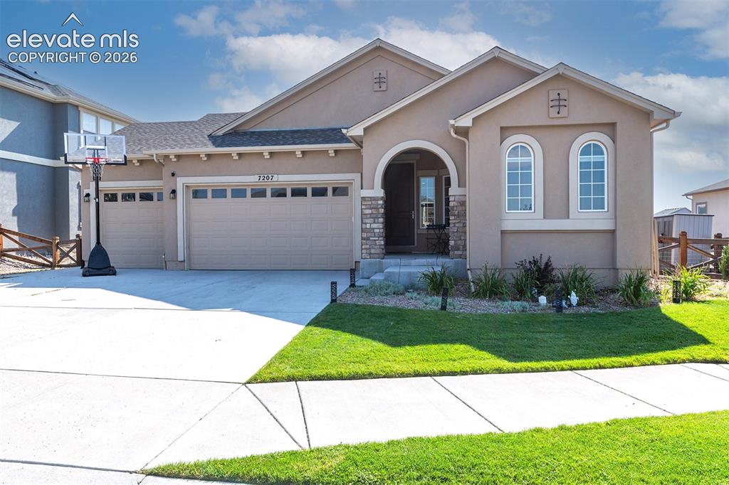 Caption: Stucco exterior with stone accenting, arched entry, two-car garage, and manicured front lawn