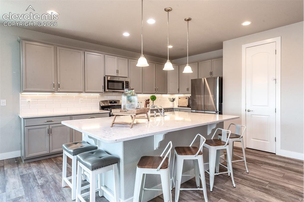 Image 10 of 43: Kitchen featuring gray cabinetry, stainless steel appliances, a white subwa