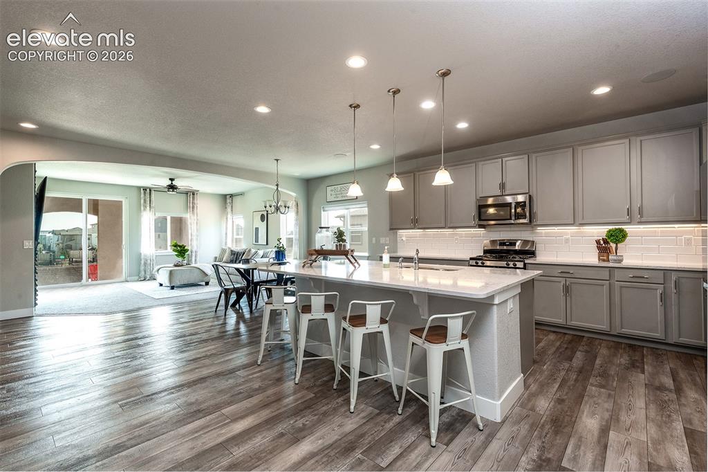 Image 11 of 43: Kitchen featuring a center island with pendant lighting, gray cabinetry, st