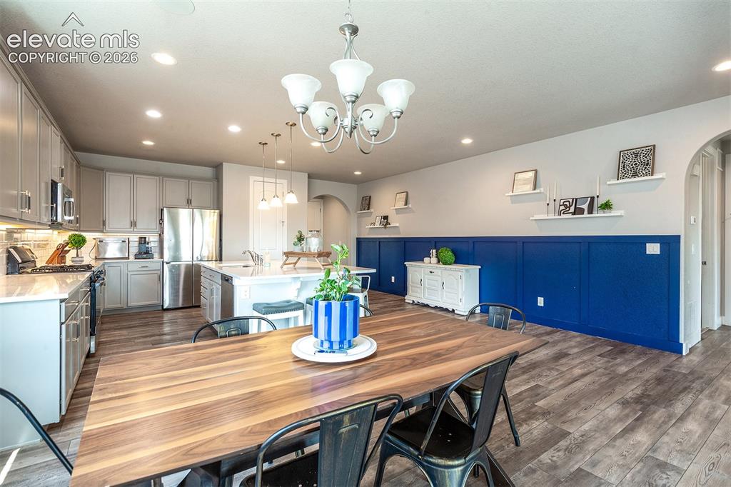 Image 13 of 43: Dining area featuring a wood-finish table, a five-light chandelier, and mul