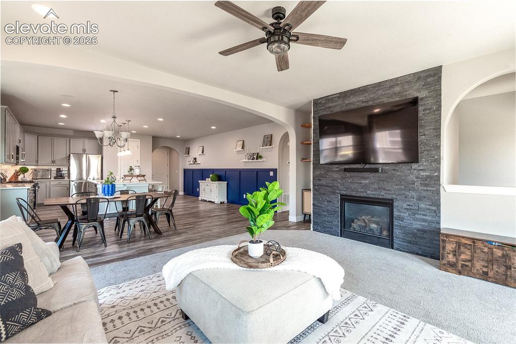 Image 15 of 43: Open-concept living space, archway details, stone front gas fireplace, wall