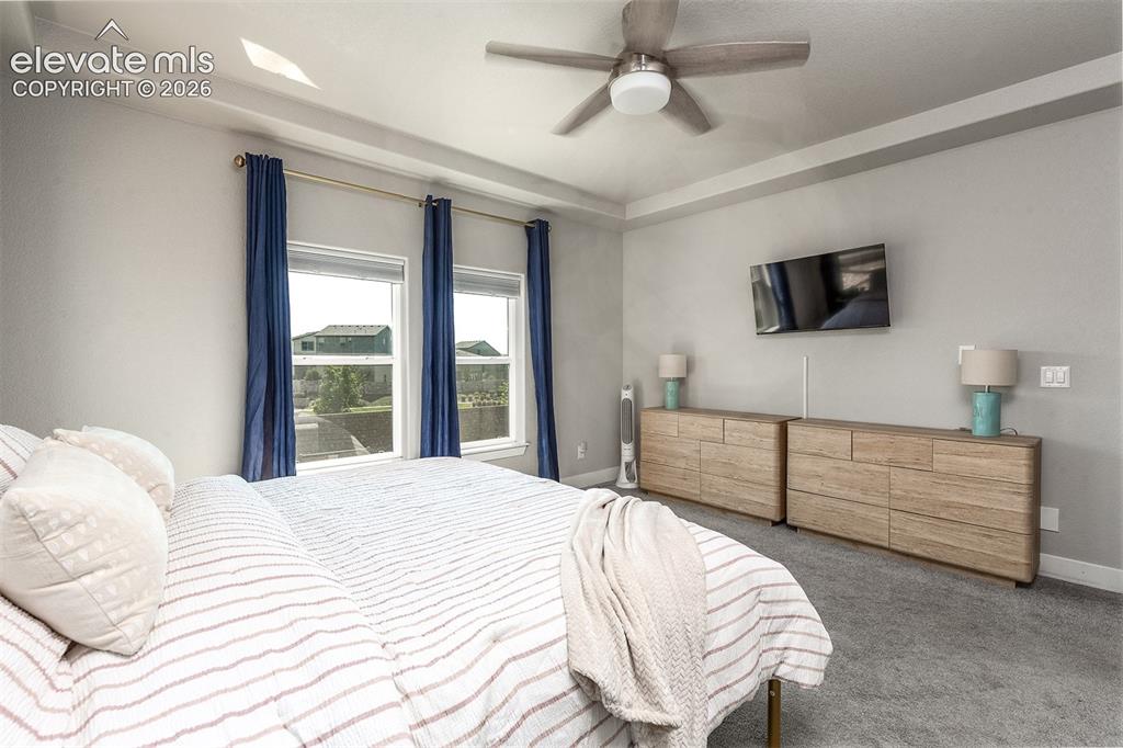 Image 19 of 43: Tray ceiling with recessed lighting, two windows with blinds, ceiling fan, 