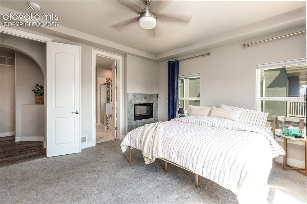 Image 20 of 43: Dual sided gas fireplace with stone surround, ceiling fan, arched doorway, 