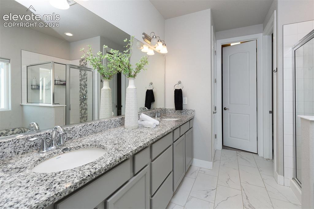 Image 21 of 43: Dual vanity with granite countertops, light grey cabinetry, and chrome fixt