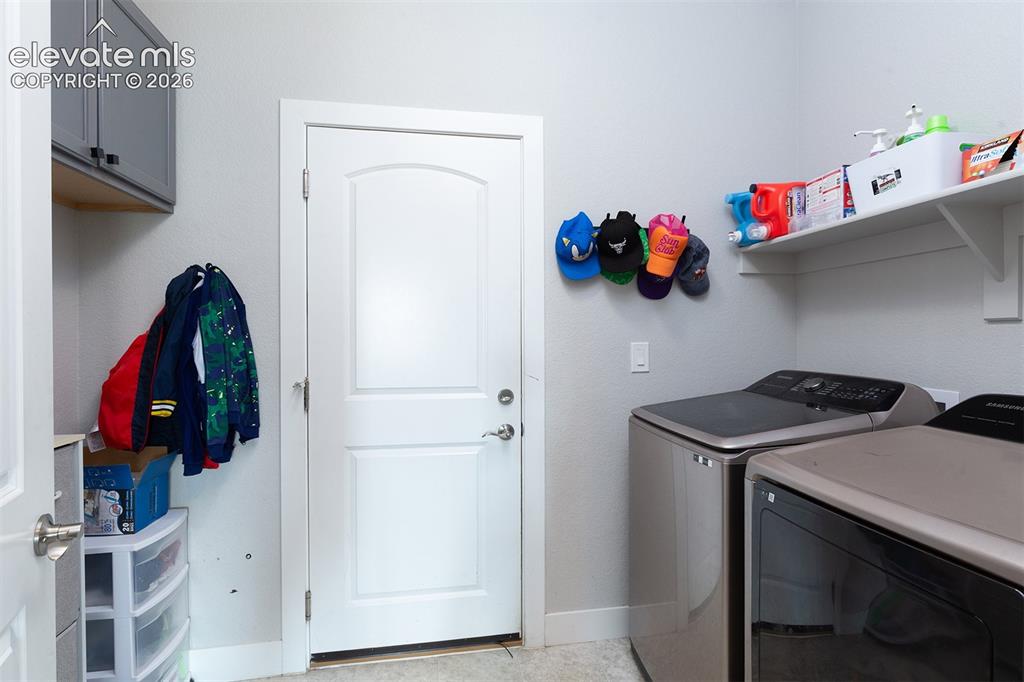 Image 23 of 43: Main-level Laundry area featuring wall-mounted cabinetry, garage entry, and