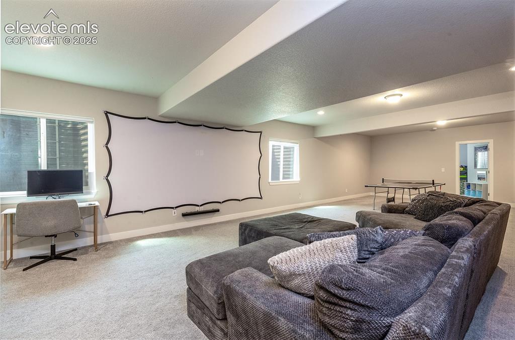 Image 24 of 43: Basement Level Family Room featuring a projector screen, windows provide na
