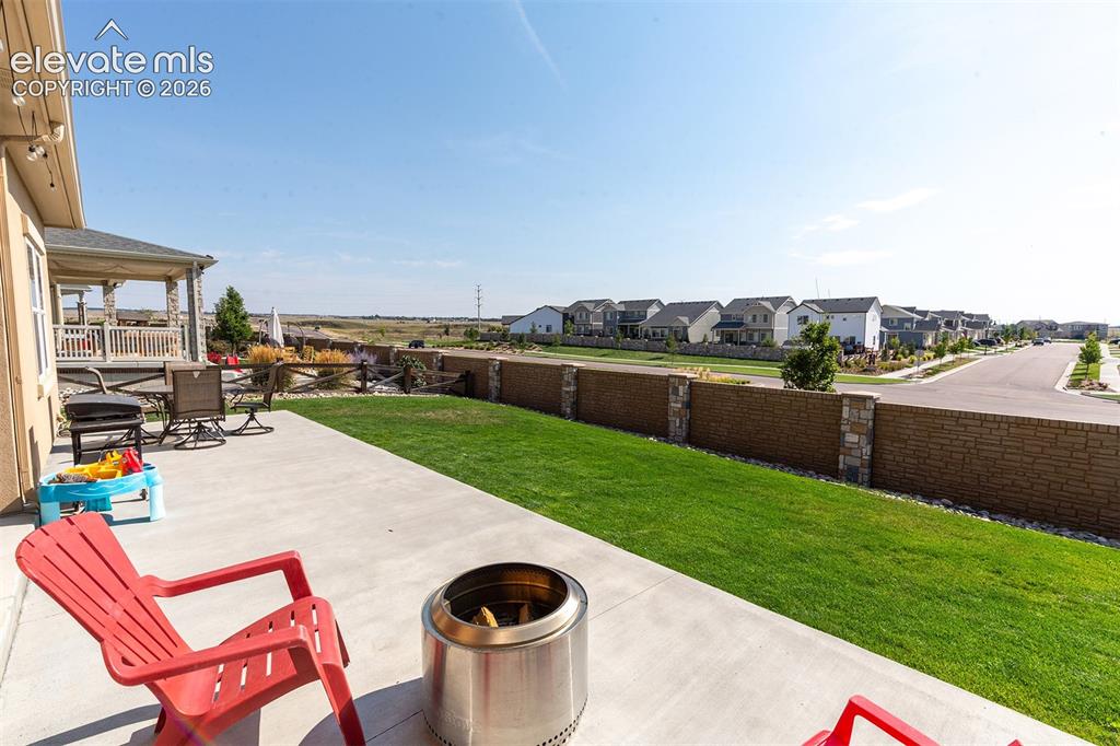 Image 32 of 43: Expansive concrete patio with string lighting, adjacent to a manicured lawn