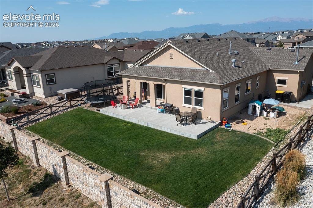 Image 33 of 43: Expansive backyard featuring a large paved patio, manicured lawn, and a sto