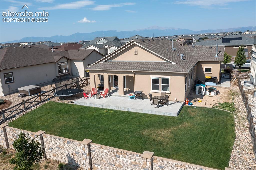 Image 37 of 43: Expansive backyard featuring a concrete patio, a manicured lawn, and a ston