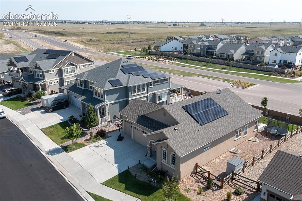 Image 38 of 43: Residential property with solar panels, attached garage, and paved driveway