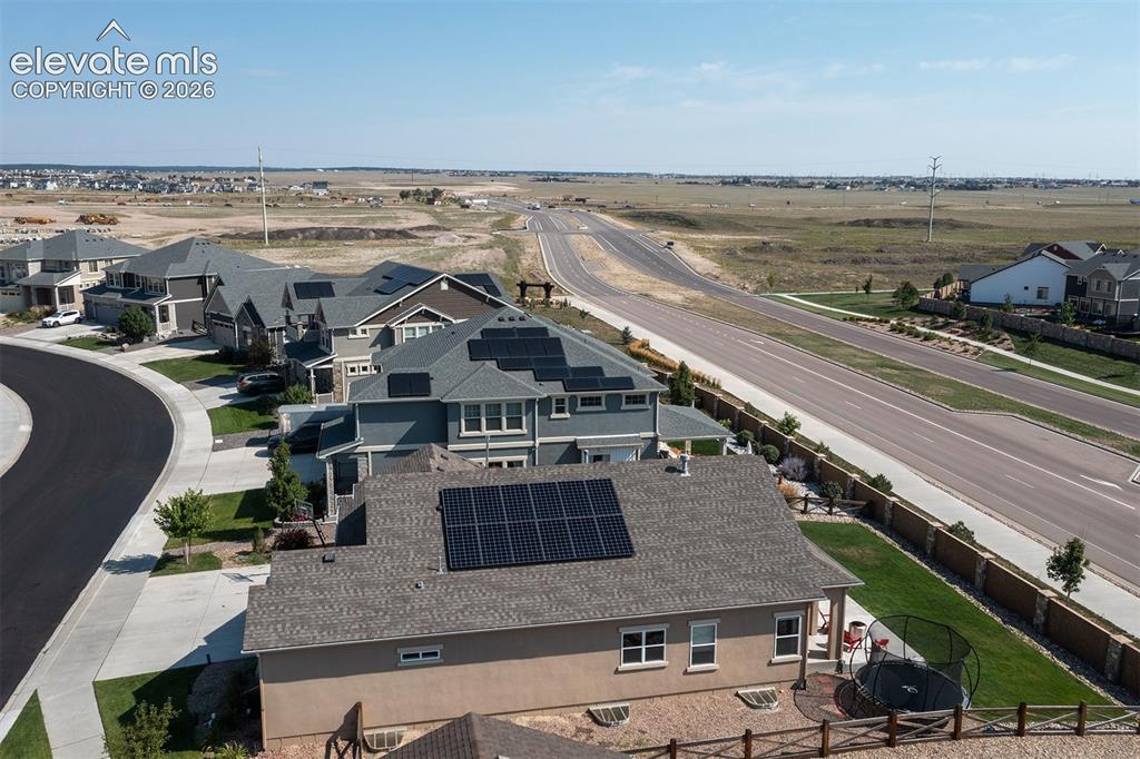 Image 39 of 43: Asphalt shingle roof with solar panels, stucco exterior, rear patio with pa