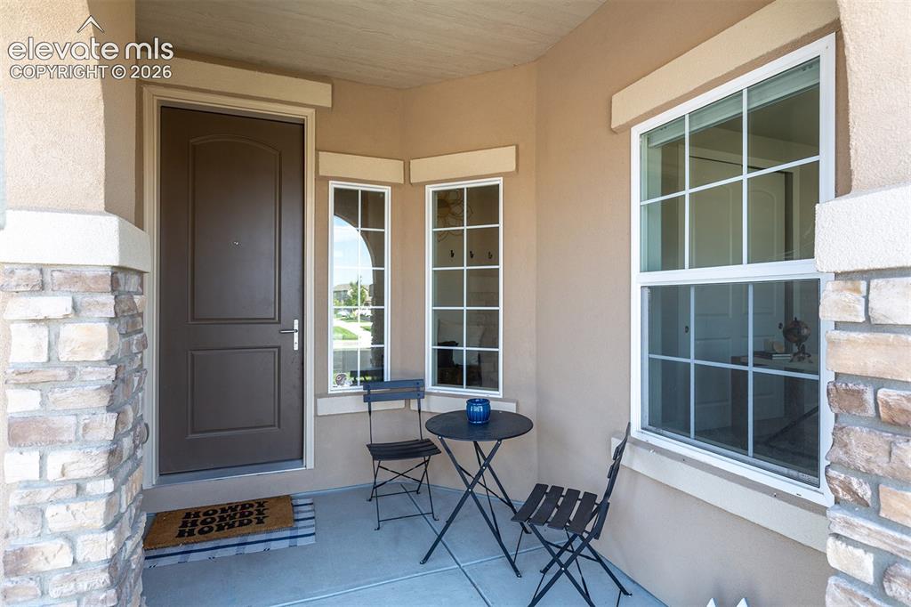 Image 4 of 43: Covered entry featuring a paneled door, stone-clad pillar, and grid-pattern