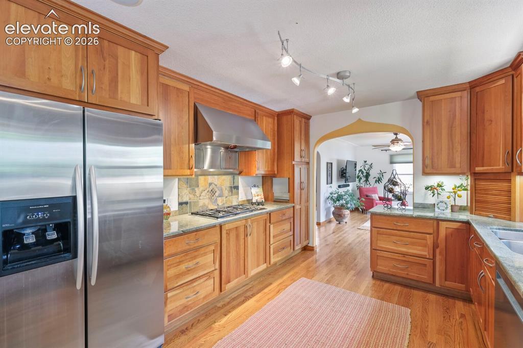 Image 11 of 50: Kitchen featuring wood cabinetry, stainless steel appliances, granite count