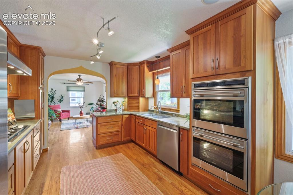 Image 12 of 50: Kitchen featuring wood cabinetry, stainless steel appliances, granite count