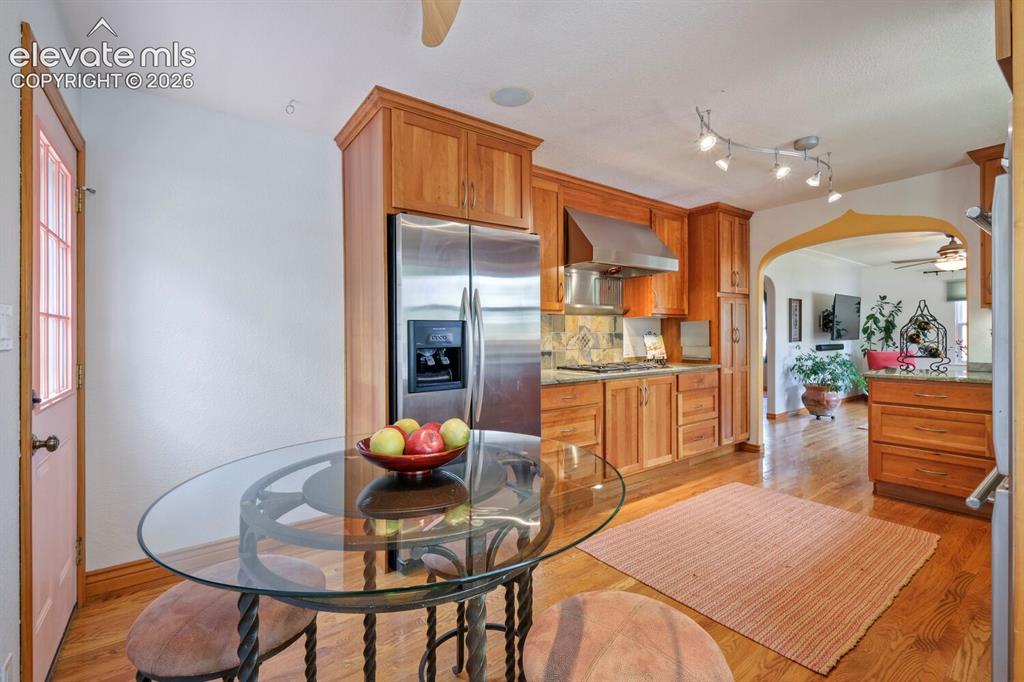 Image 14 of 50: Kitchen featuring wood cabinetry, stainless steel range hood, built-in gas