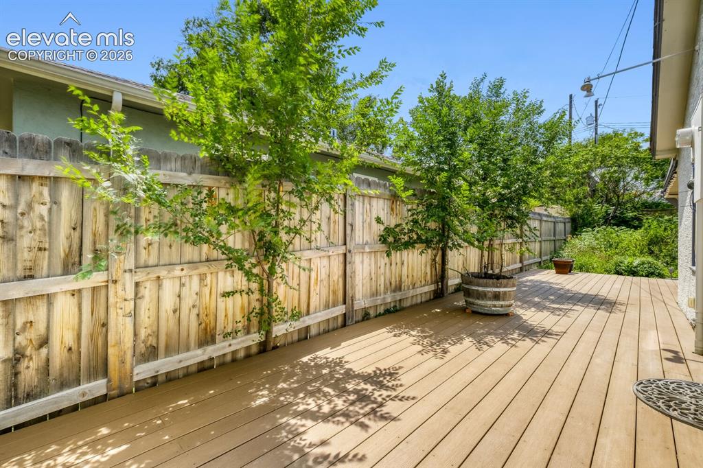 Image 23 of 50: Covered back patio featuring wood-finish decking, ceiling fan, recessed lig