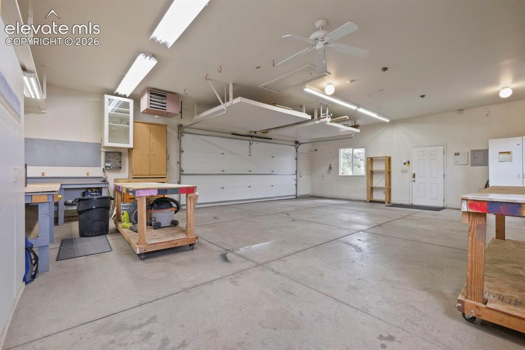 Image 30 of 50: Spacious garage featuring a concrete floor, built-in white cabinetry, overh