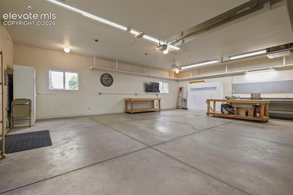 Image 31 of 50: Spacious garage featuring a concrete floor, multiple fluorescent light fixt