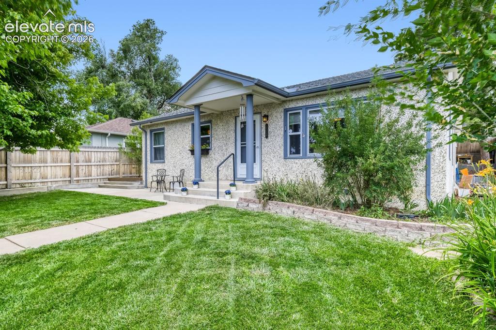 Image 4 of 50: Charming stucco exterior with a covered entry, mature landscaping, and a co
