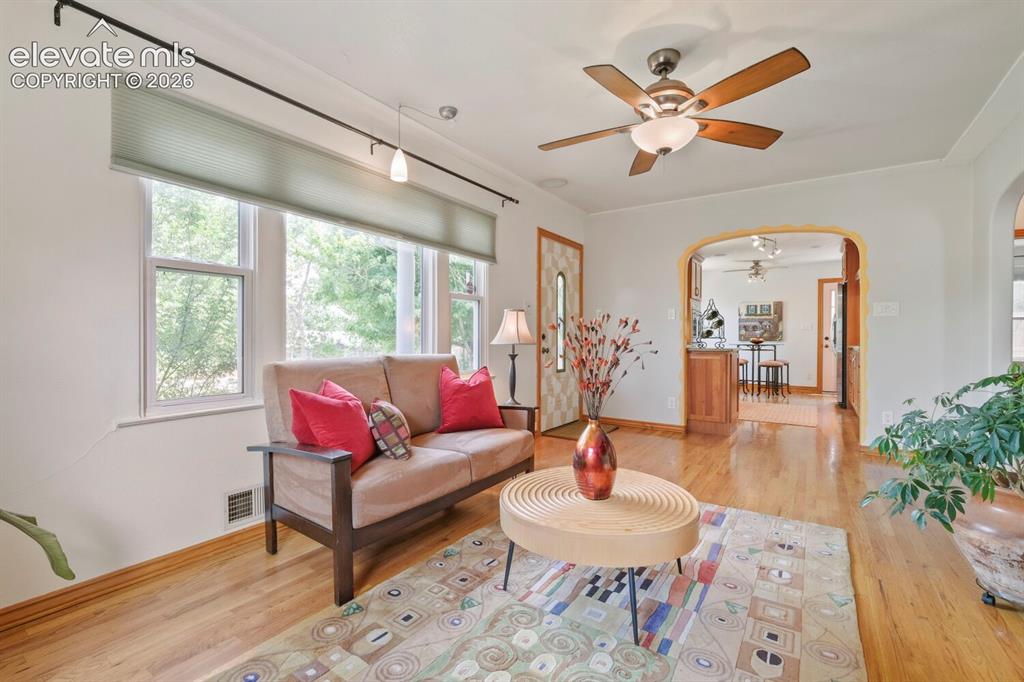 Image 8 of 50: Living area featuring wood-finish flooring, a ceiling fan with integrated l