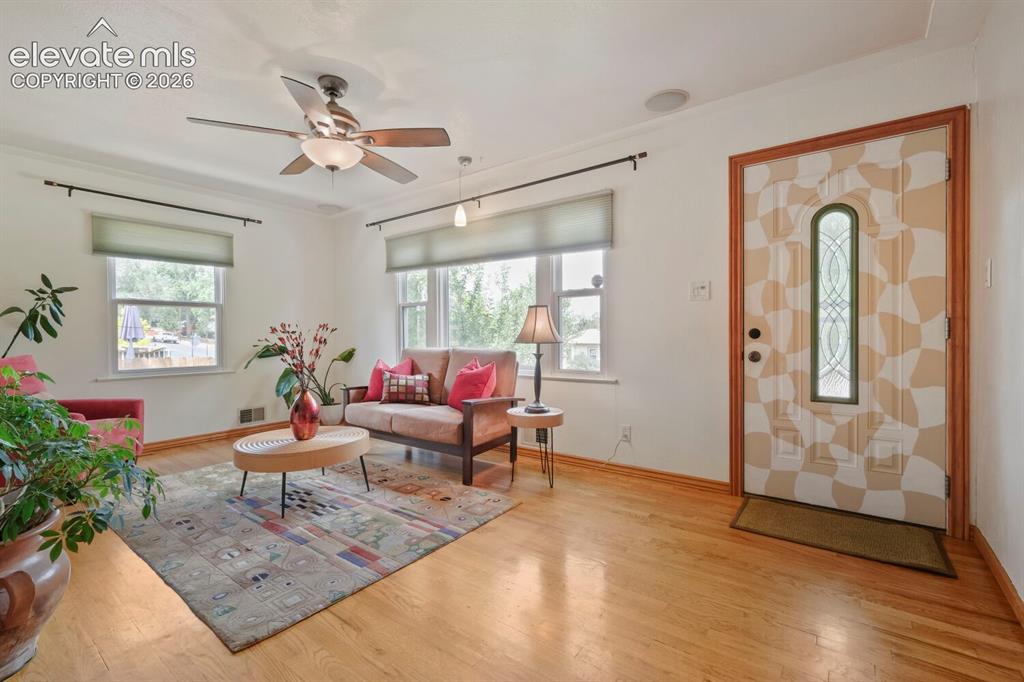 Image 9 of 50: Living area featuring warm wood-finish flooring, a ceiling fan with integra