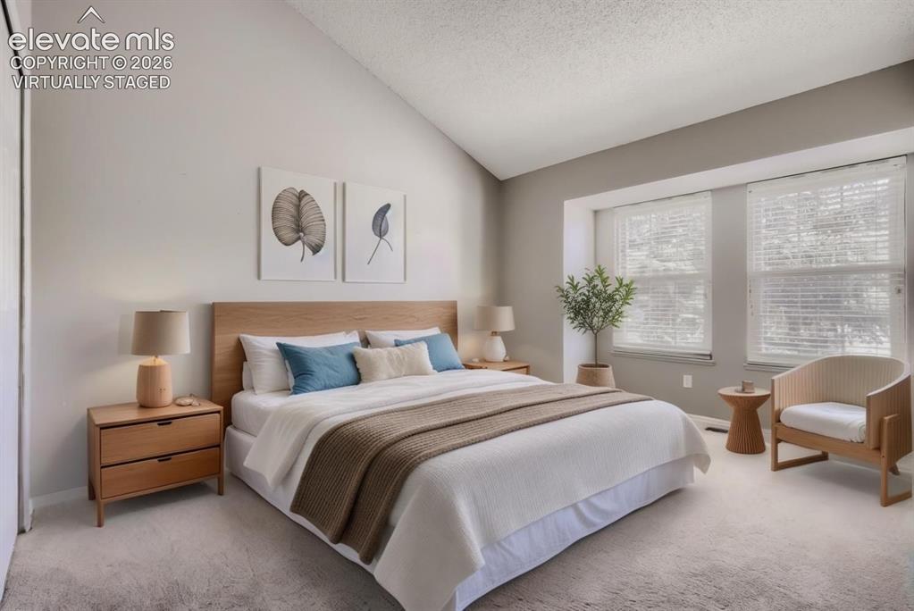 Image 10 of 28: Vaulted ceiling bedroom featuring a light wood-finish bed frame, two large 