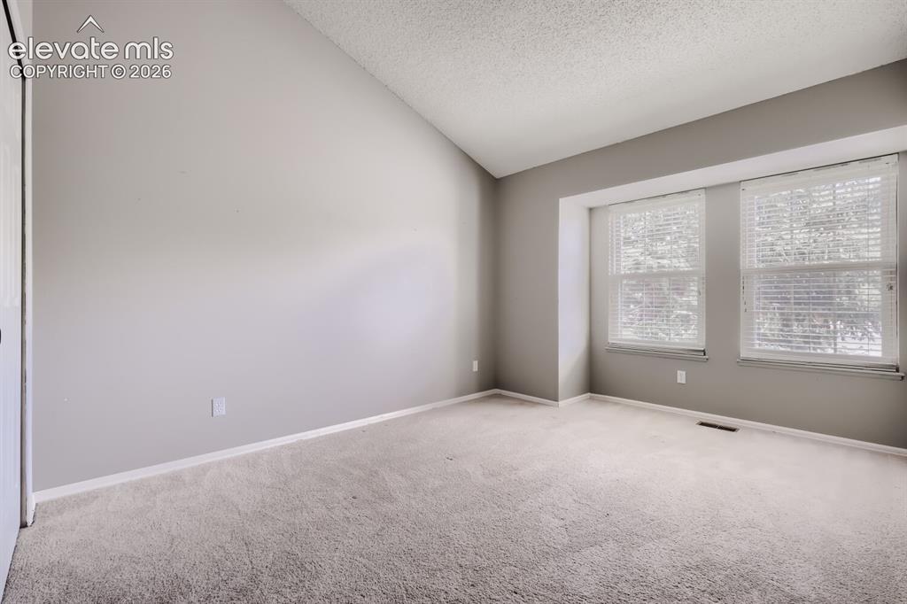 Image 11 of 28: Spacious room with vaulted ceiling and neutral wall paint