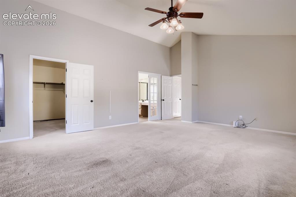Image 16 of 28: Spacious carpeted room featuring a vaulted ceiling and a ceiling fan with i
