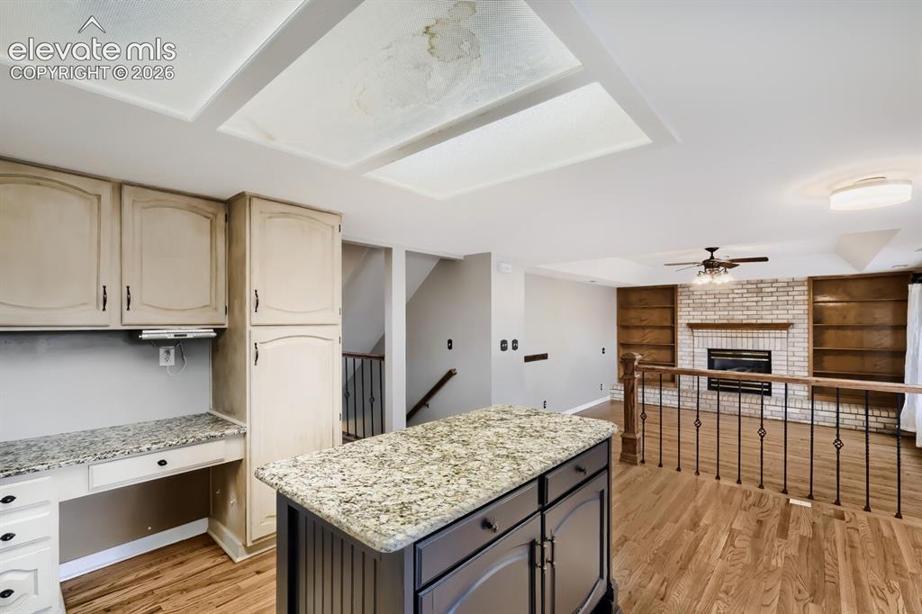 Image 18 of 28: Kitchen island with granite countertop, wood-finish flooring, built-in desk