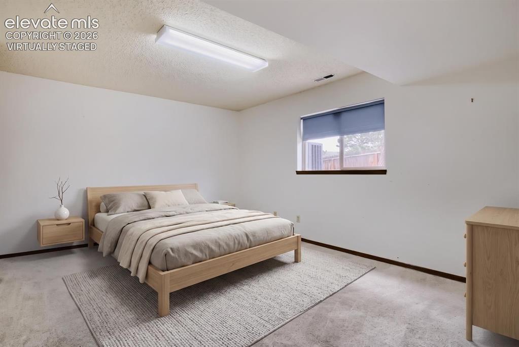 Image 19 of 28: Carpeted room with a horizontal window featuring a roller shade and wood tr