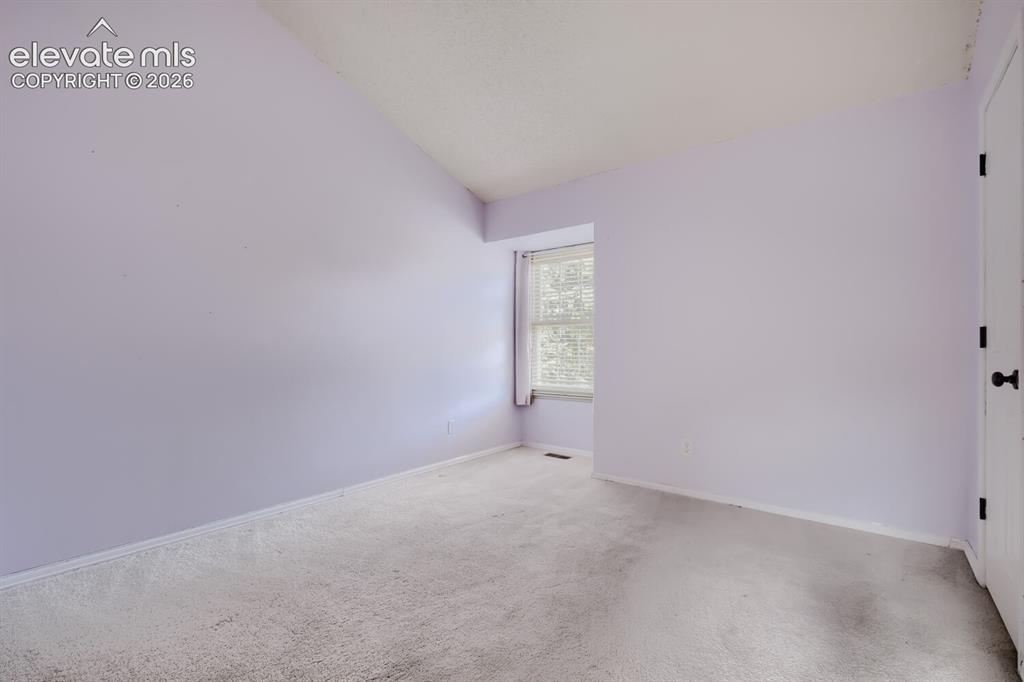 Image 21 of 28: Carpeted room with a vaulted ceiling, a window featuring blinds, and a whit