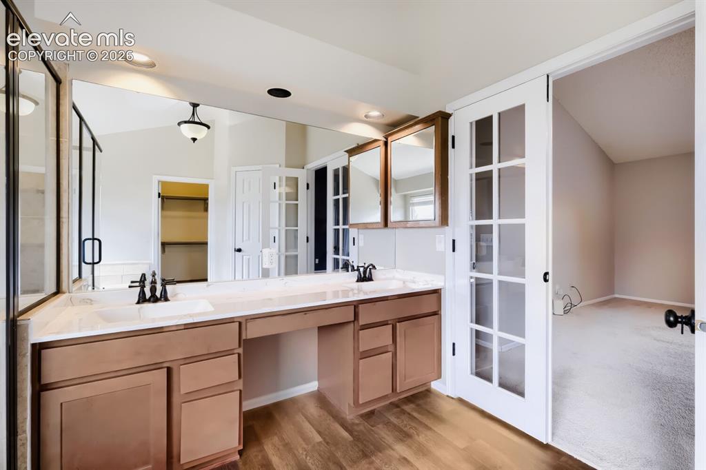 Image 22 of 28: Dual vanity with integrated sinks, light-toned countertop, and wood-finish 