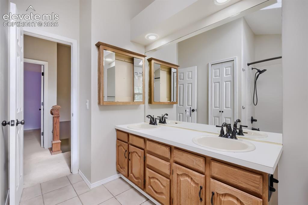 Image 23 of 28: Bathroom featuring a dual vanity with oak cabinetry, integrated sinks, and 