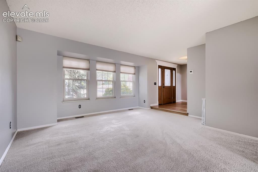Image 6 of 28: Living area featuring light gray walls and plush carpeting