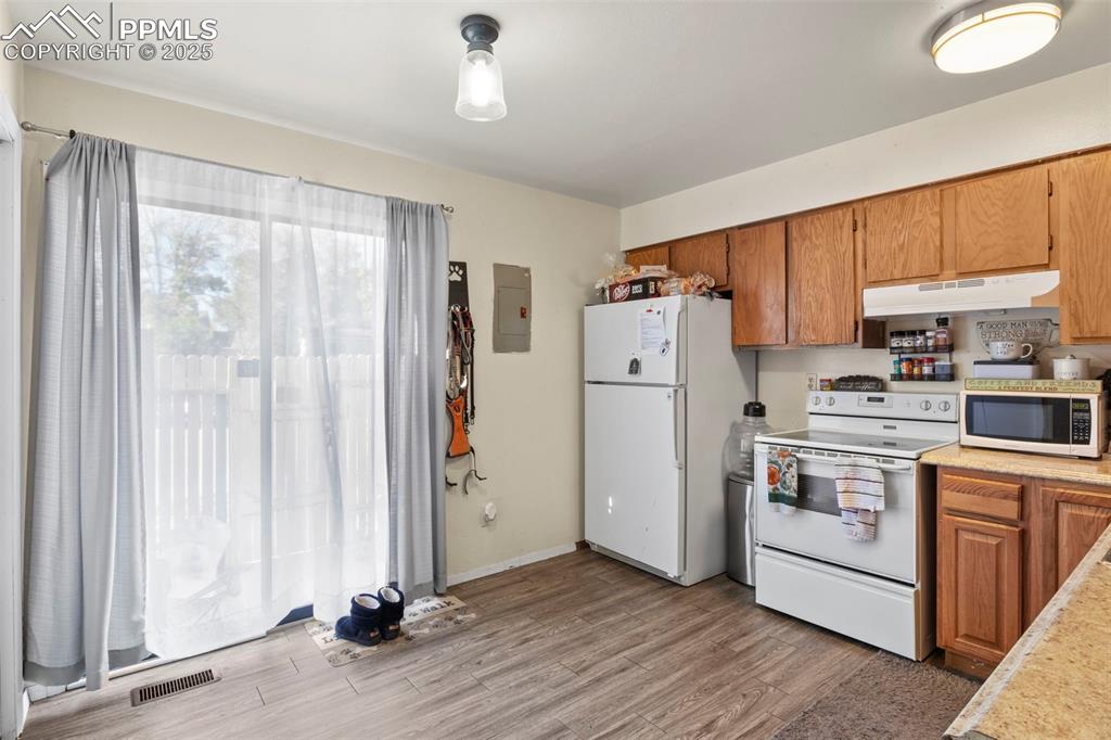 Image 12 of 31: Kitchen featuring brown cabinetry, light countertops, white appliances, lig