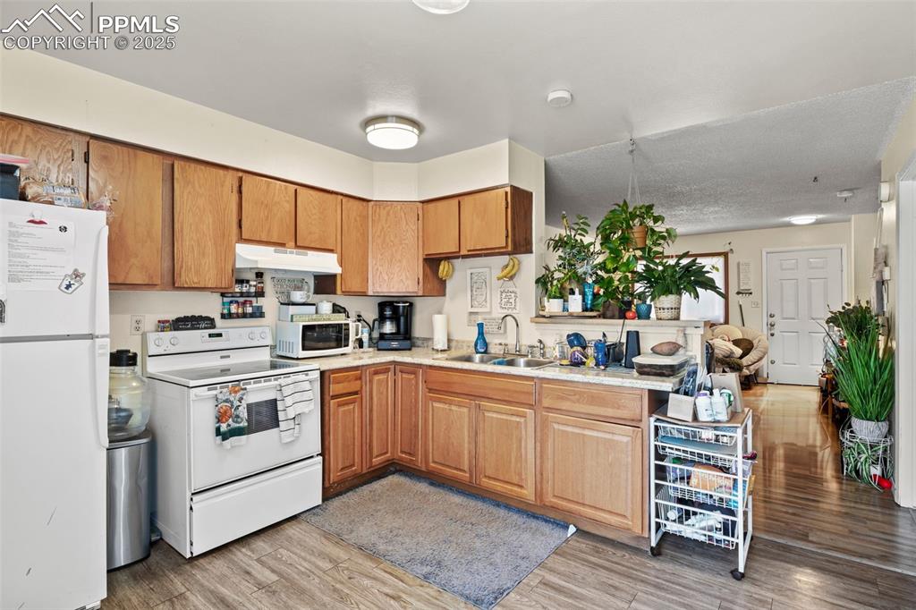 Image 13 of 31: Kitchen with white appliances, light wood-style flooring, brown cabinetry, 